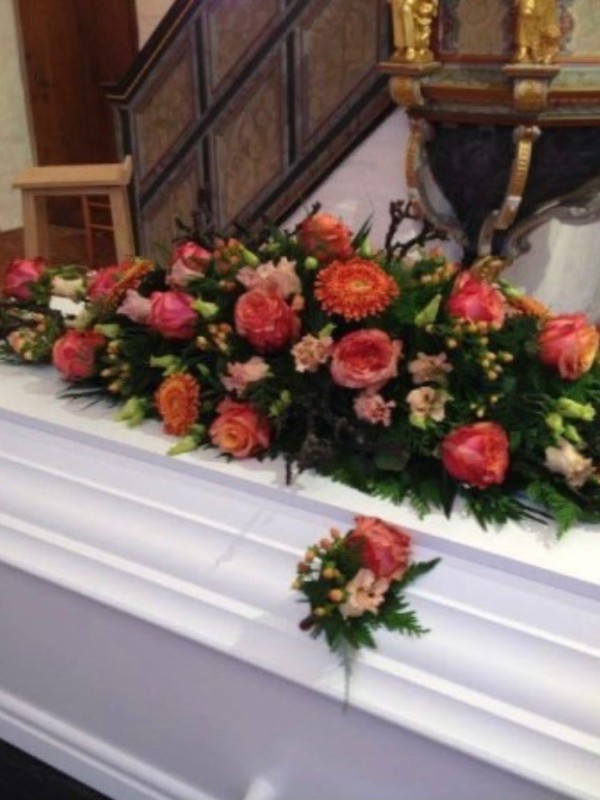 Kistepynt med sæsonens blomster i koralfarvet nuancer