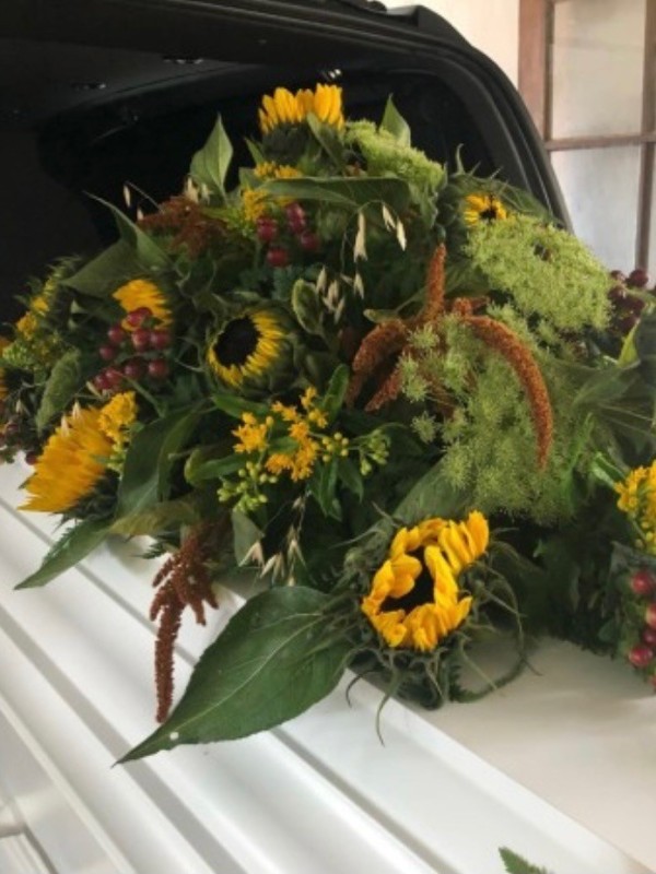 Kistepynt med sæsonens blomster i gule nuancer