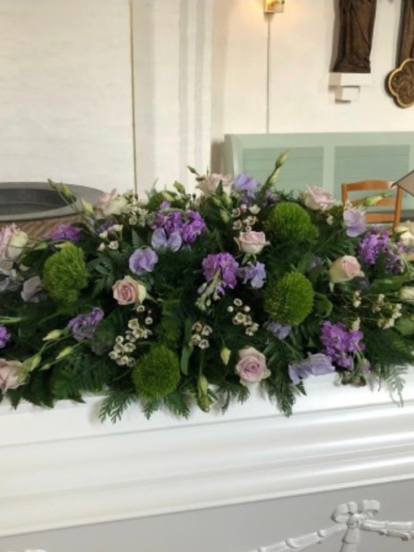 Kistepynt med sæsonens blomster i lilla nuancer