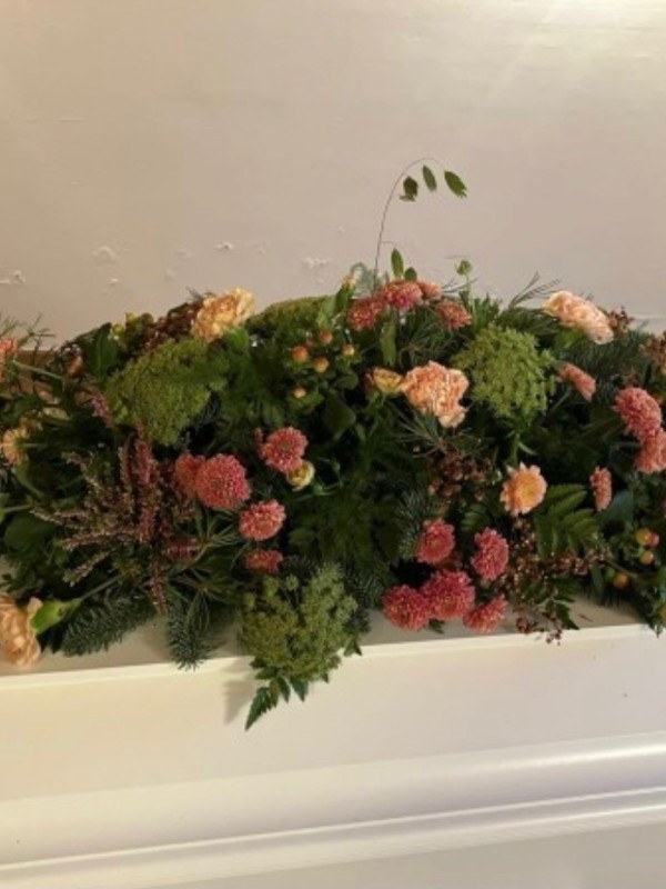 Kistepynt med sæsonens blomster i laksefarvet nuancer